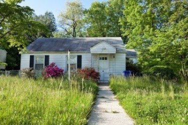 $11379707-front-vew-of-unmowed-lawn-of-an-abandoned-foreclosed-cape-cod-style-house-in-suburban-m.jp
